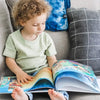 Un enfant découvrant son livre personnalisé sur les métiers qu'il a reçu comme cadeau de Noël.