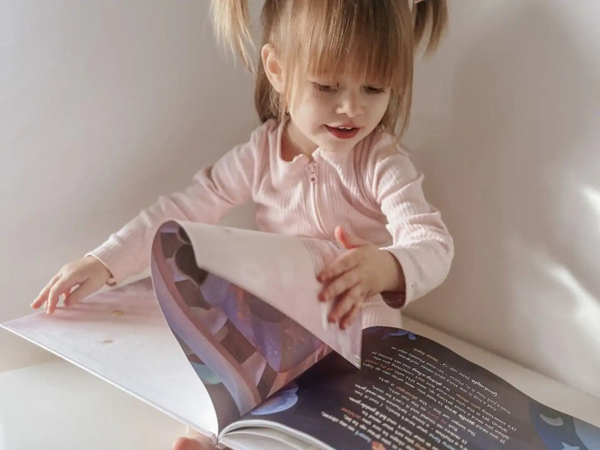 Une petite fille qui feuillette son livre offert pour la fête des mères, à propos des futurs métiers.