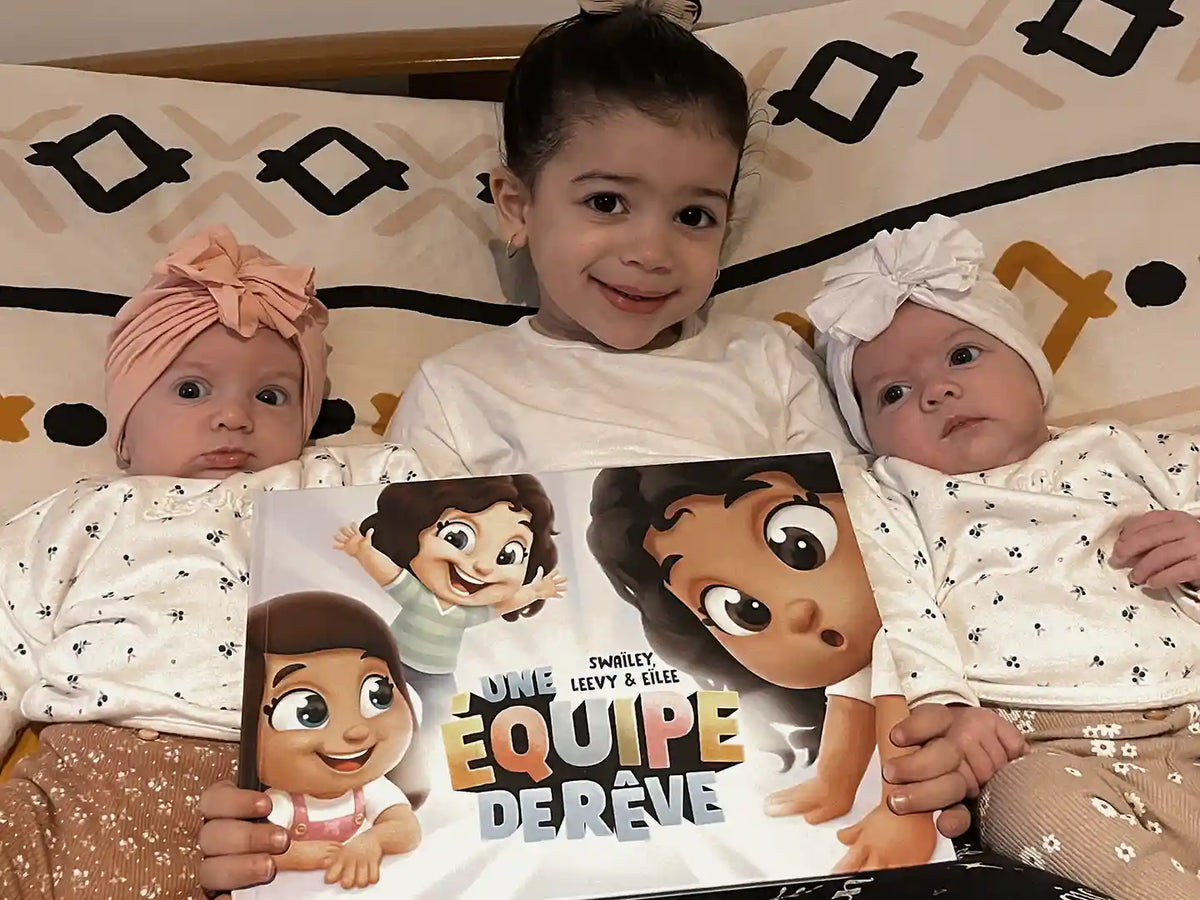 Un grand frère et ses petites soeurs avec leur livre personnalisé pour les enfants de chez Hourra Héros.