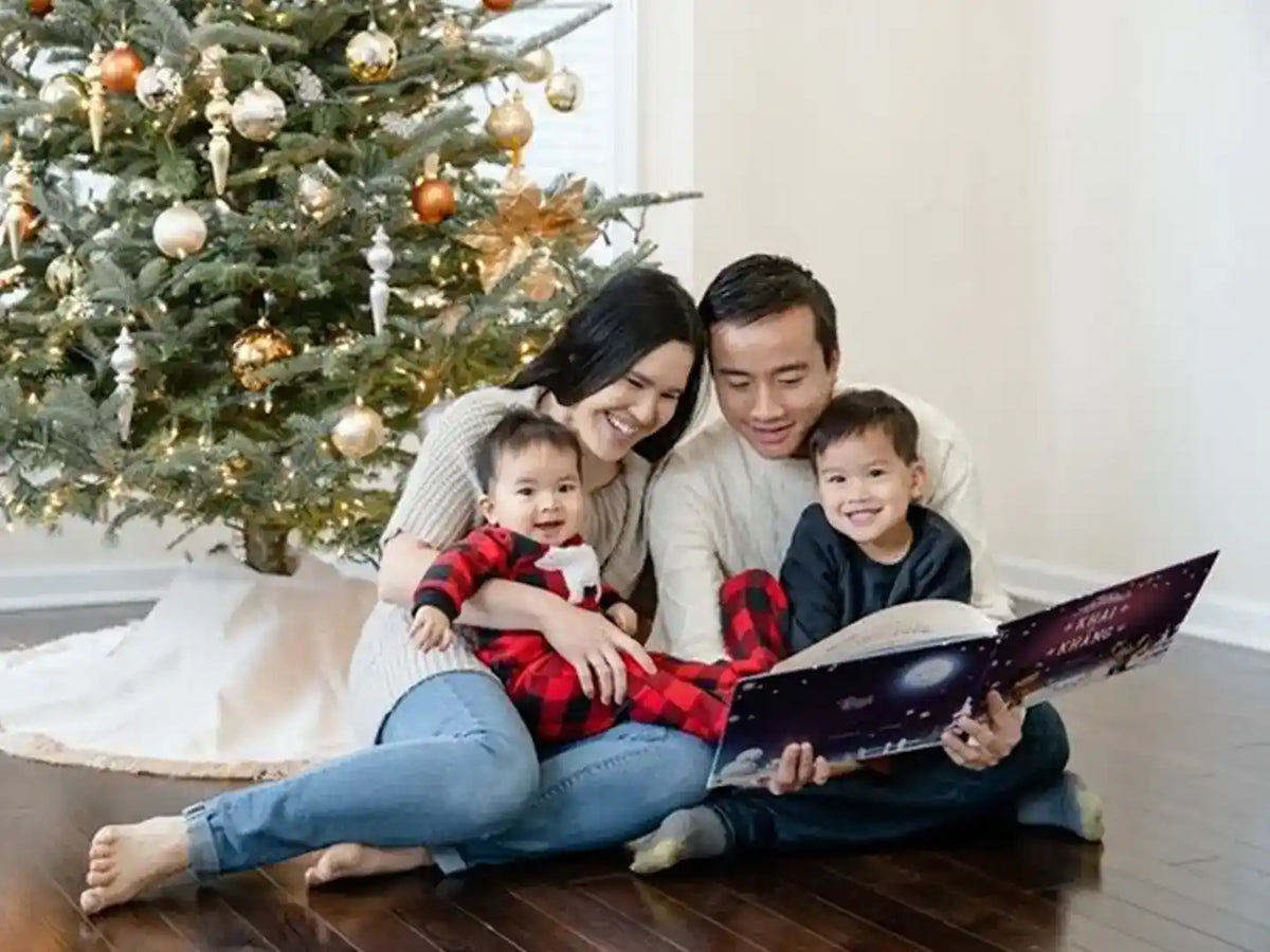 Une famille lisant son livre perosnnalisé de Noël sous le sapin.