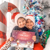Deux petits tenant dans leurs mains le meilleur cadeau de Noêl pour les enfants : un livre Hourra Héros.