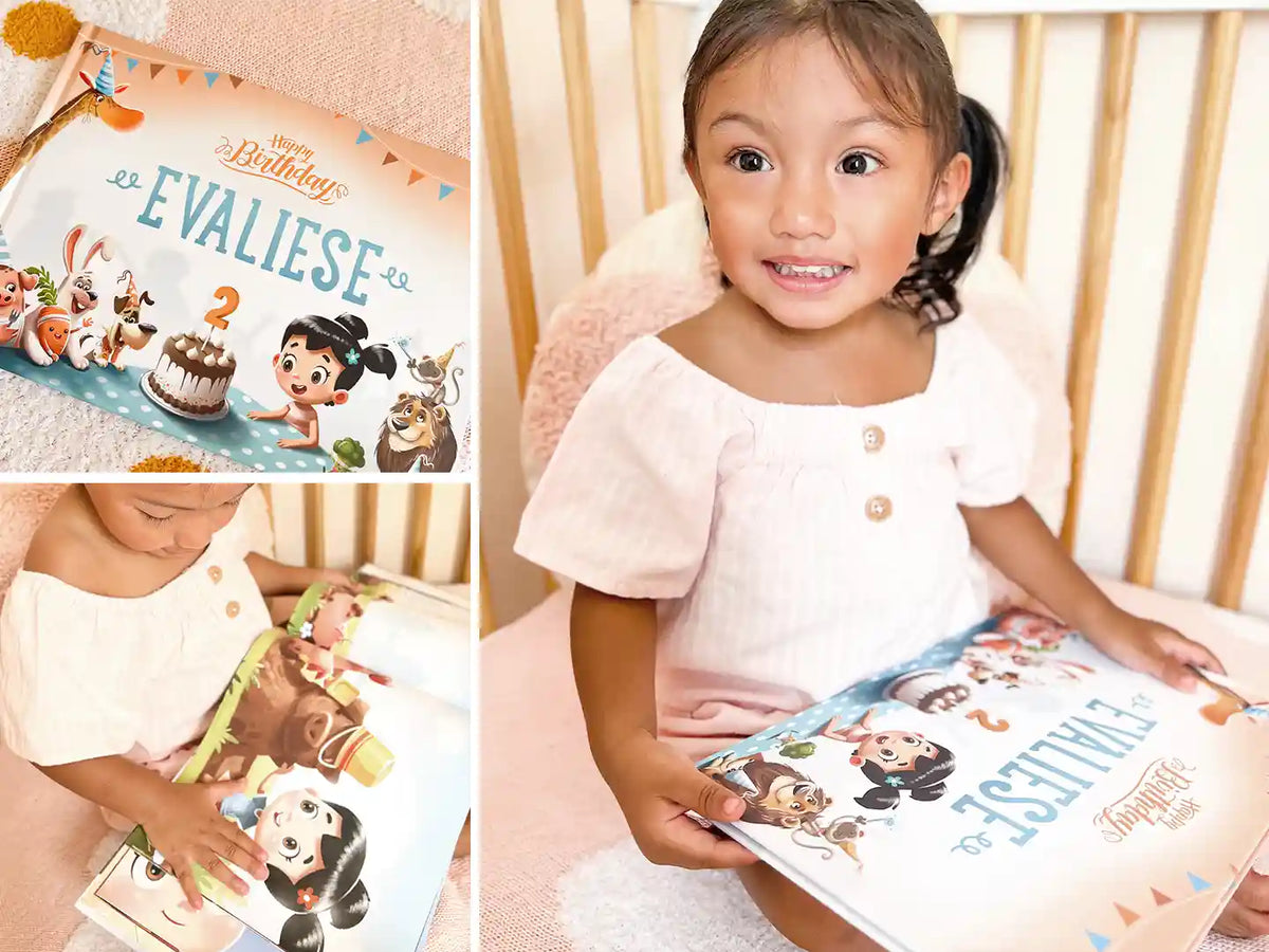Une petite fille souriante de deux ans avec son livre d'anniversaire personnalisé.