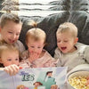 Les enfants mangent du pop-corn et apprécient ce livre personnalisé pour frères et sœurs.