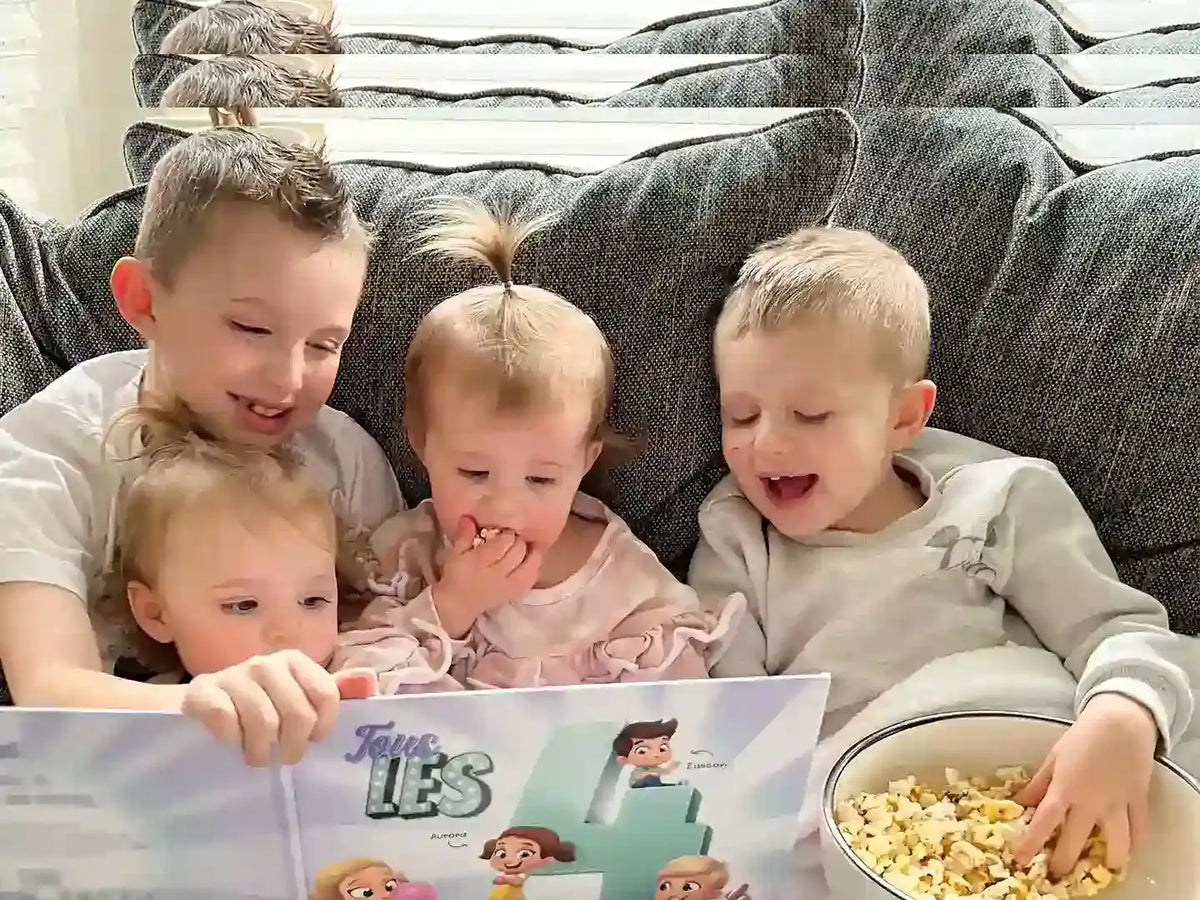 Les enfants mangent du pop-corn et apprécient ce livre personnalisé pour frères et sœurs.