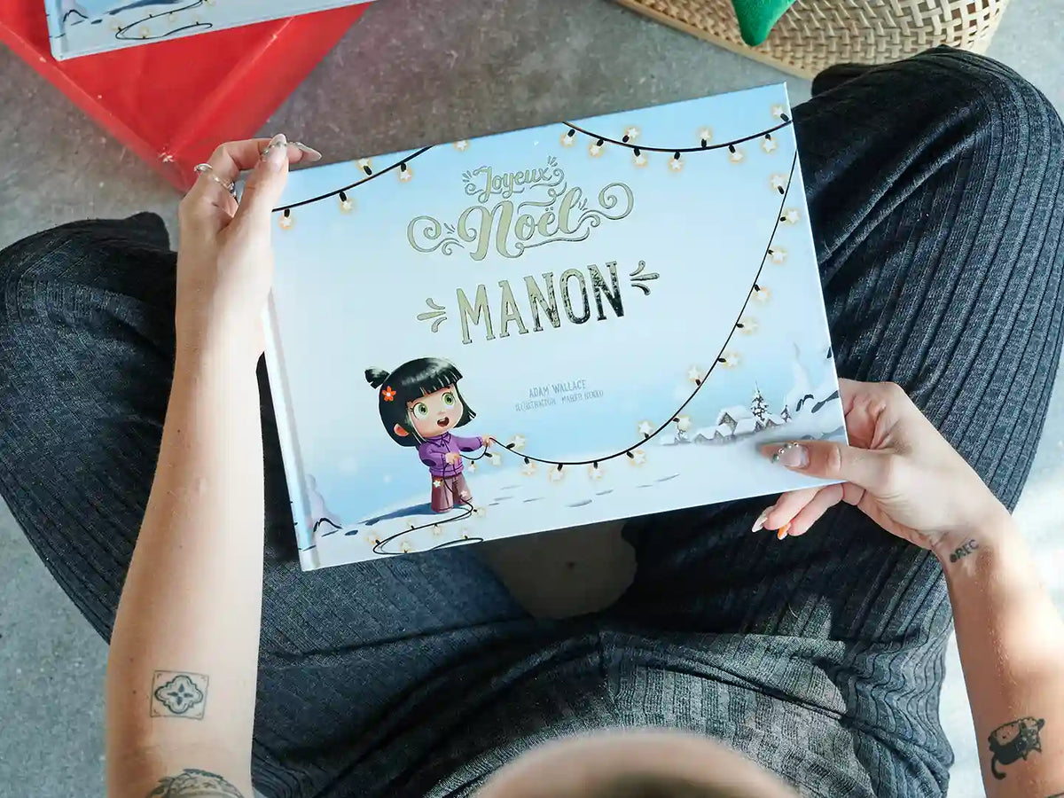 Une femme tient un livre de Noël personnalisé, qui est le meilleur cadeau de Noël pour les enfants.