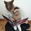 Une grande soeur qui lit à sa cadette un livre de Noël personnalisé.