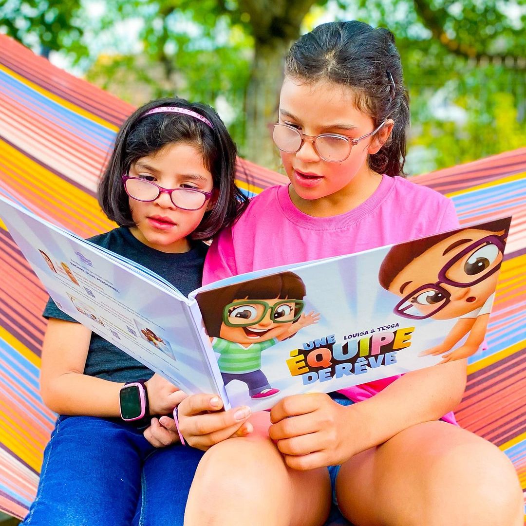 Deux sœurs en train de lire la meilleure idée de cadeau pour les enfants: un livre personnalisé de chasse au trésor, rempli d'histoires amusantes.