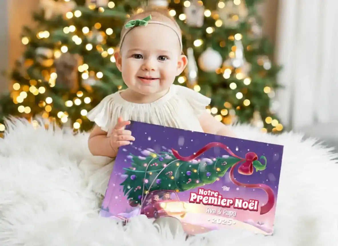 Bébé assis devant un sapin tenant le livre personnalisé “Notre Premier Noël 2025” avec Ava et Papa.