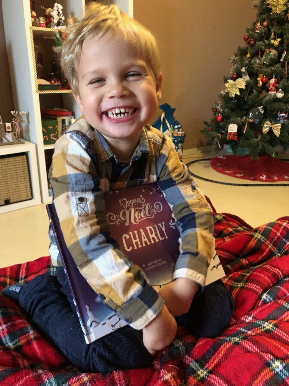 Ce petit garçon sourit car il a reçu comme cadeau de Noël un livre personnalisé.